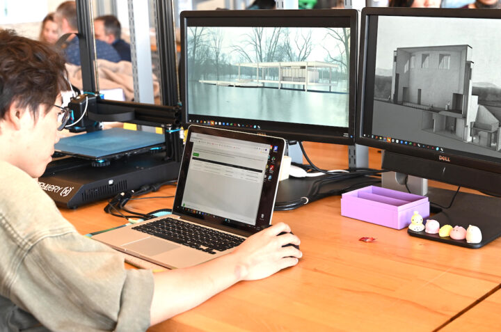 Student in front of computer screen showing building rendering